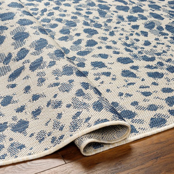 a blue and white leopard print rug on top of a wooden floor next to a wood floor