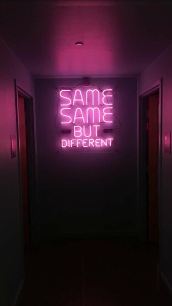 a neon sign that says same same but different on the side of a wall in a hallway