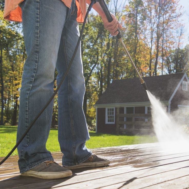 a person using a pressure washer on a deck