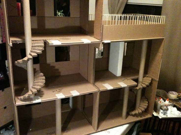 a cardboard doll house with stairs and windows in the middle of it's room