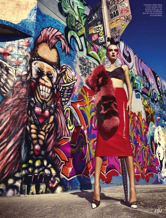 a woman standing in front of a wall with graffiti on it