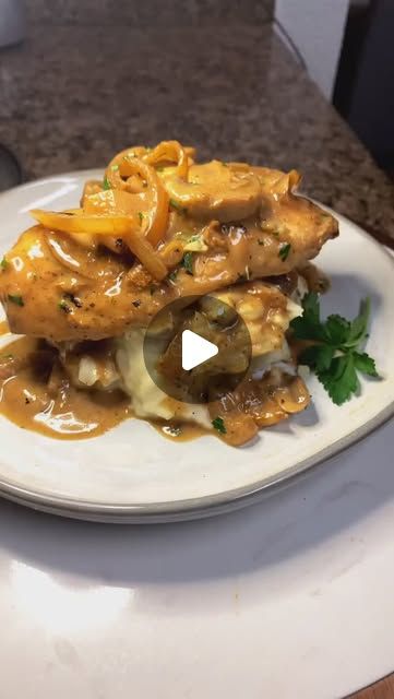 a white plate topped with meat covered in gravy and sauce on top of a counter