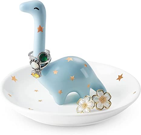 an elephant ring holder on top of a white plate with flowers and stars around it