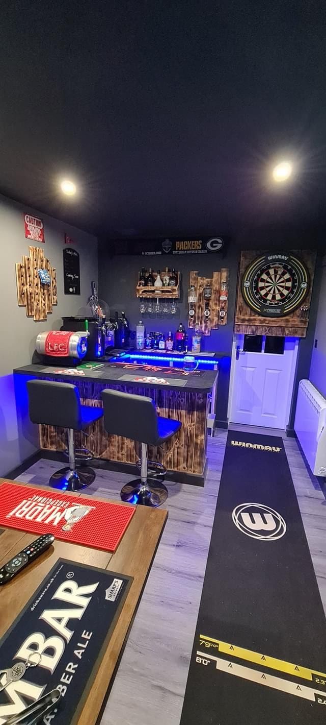 a man cave with two bar stools and various items on the floor in front of it