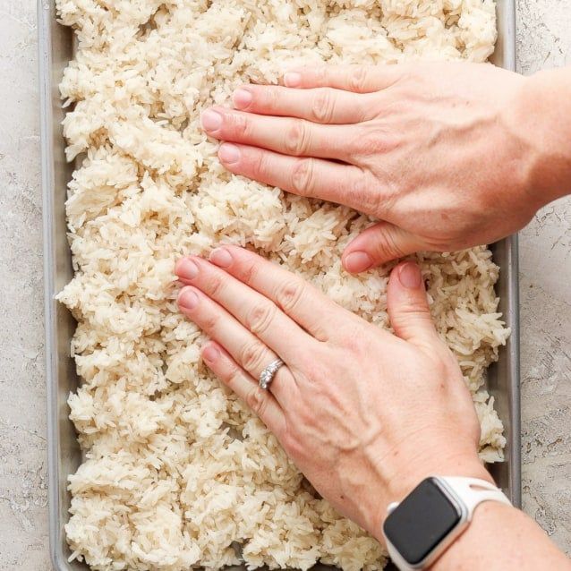 two hands touching each other over rice in a pan on a table with an apple watch