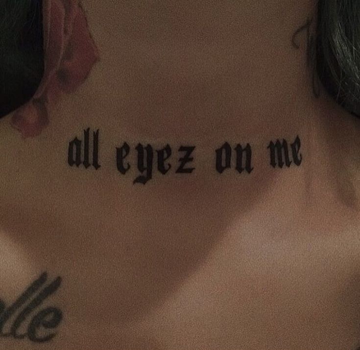 the back of a woman's neck with an all eyez on me tattoo