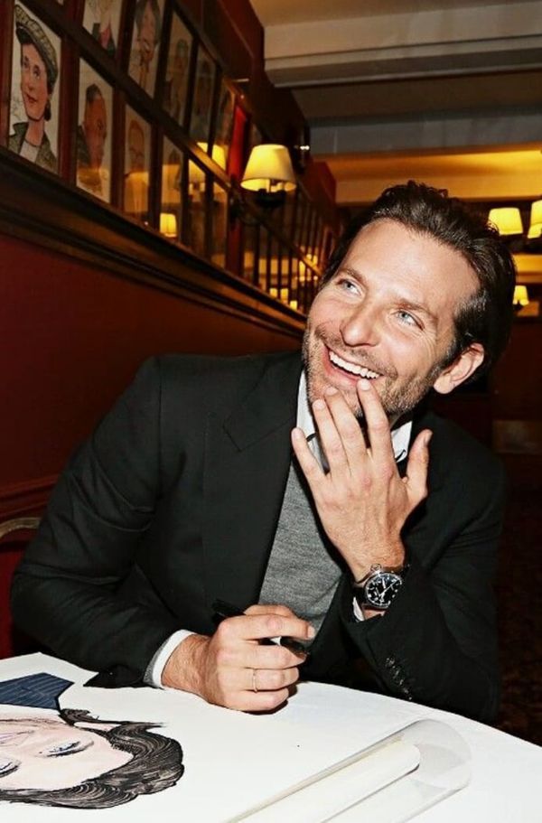 a man sitting at a table with his hand on his face and smiling for the camera