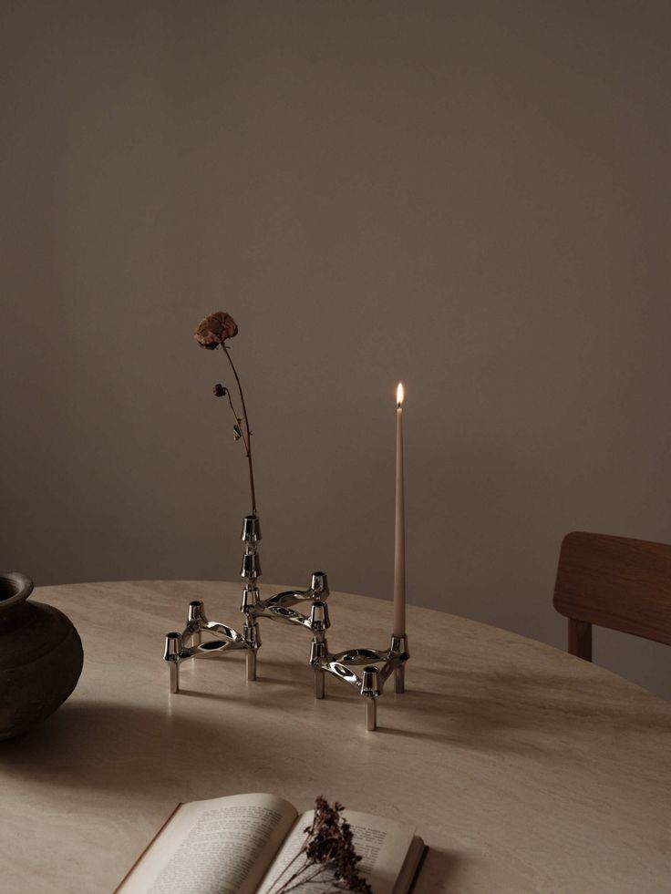 an open book sitting on top of a table next to two candles and a flower