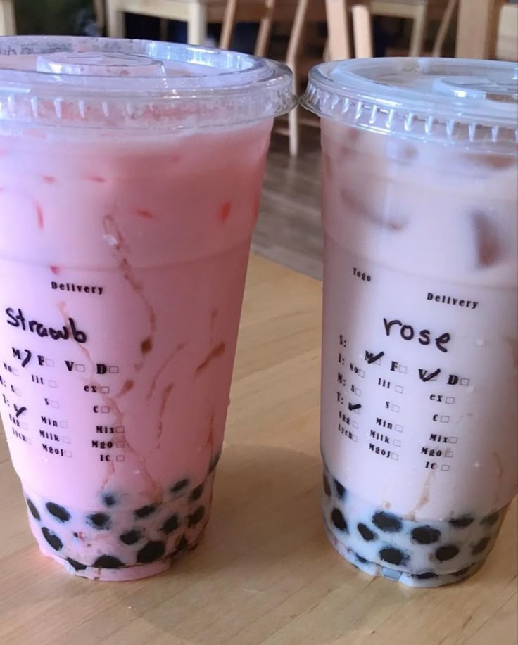 two plastic cups filled with liquid sitting on top of a wooden table next to each other