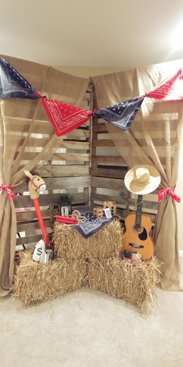 a room with hay bales and decorations on the wall, including a guitar, cowboy hat, bandana, and other items