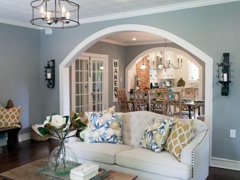 a living room filled with furniture next to a dining room table and doorway leading into a kitchen