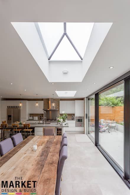 an open kitchen and dining room area with skylights above the countertop, along with large wooden table surrounded by purple chairs