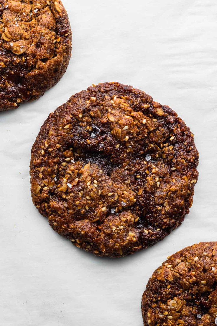 three cookies on top of a piece of parchment paper next to one cookie with nuts