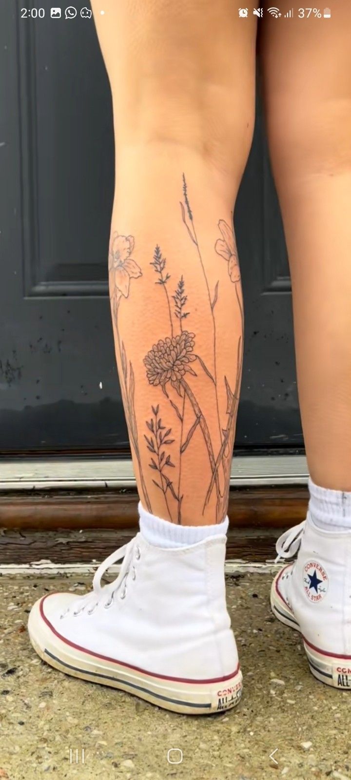 the legs and ankles of a person with tattoos on them, standing in front of a door