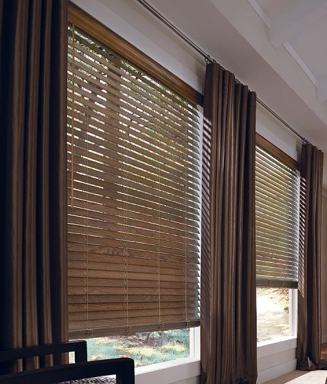 a living room filled with furniture and large windows covered in brown blinds on top of them