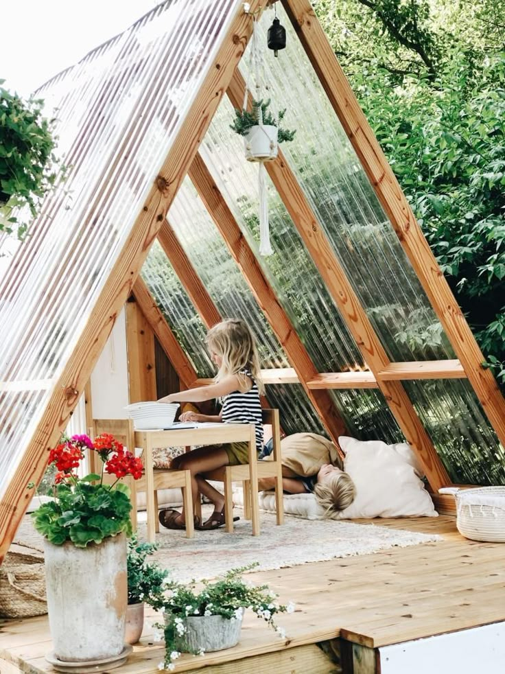 a small house made out of wood with plants in the corner and an open roof