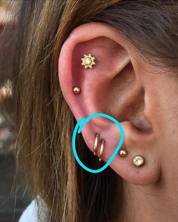 a woman wearing gold ear piercings with blue circle