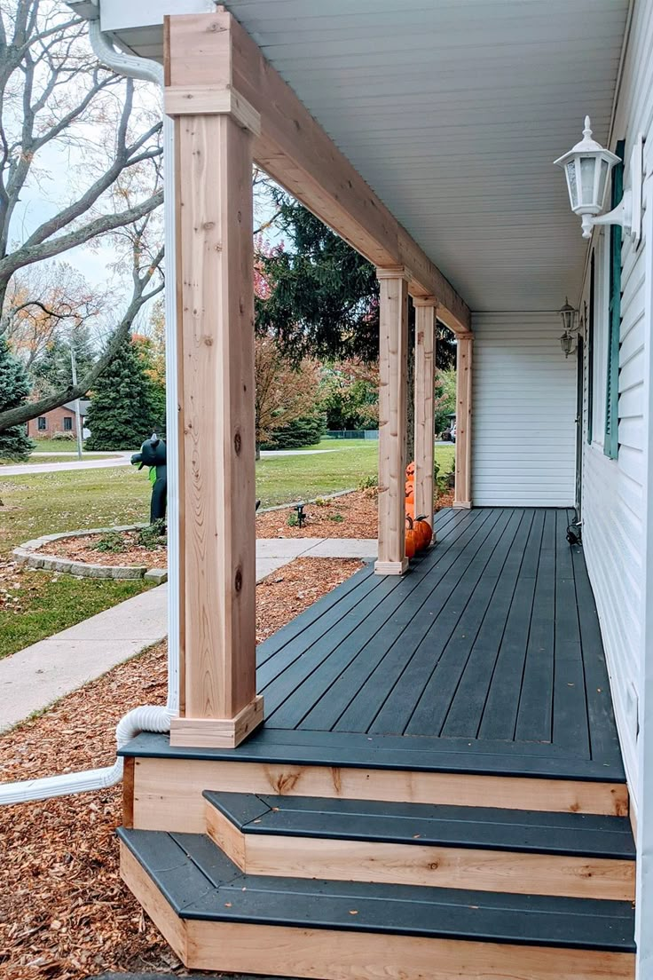 a porch with steps leading up to the front door and an orange vase sitting on top of it