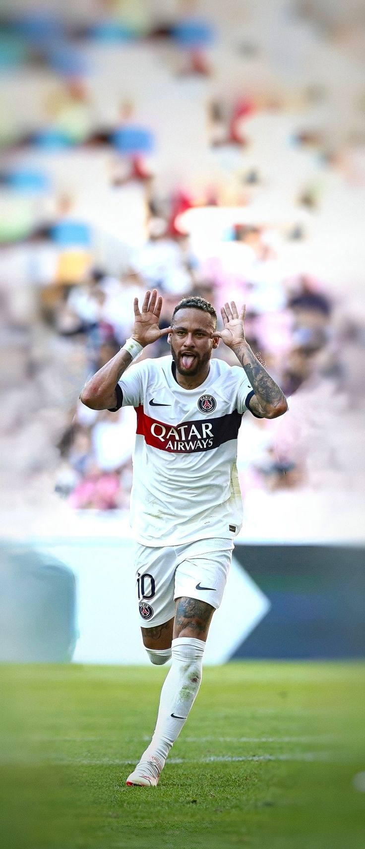 a soccer player running on the field with his hands in the air as he celebrates