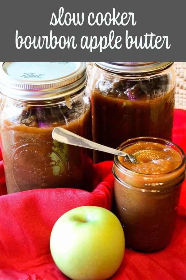 two jars filled with food sitting on top of a red cloth next to an apple