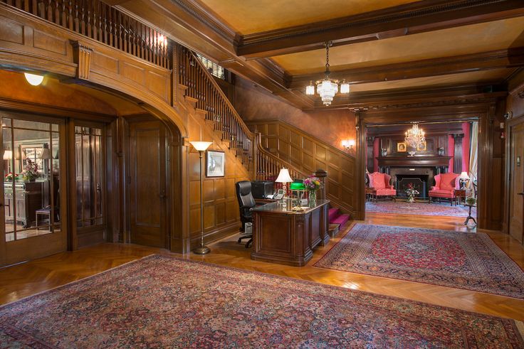 an ornate entry way with wood paneling and chandeliers on either side of the staircase