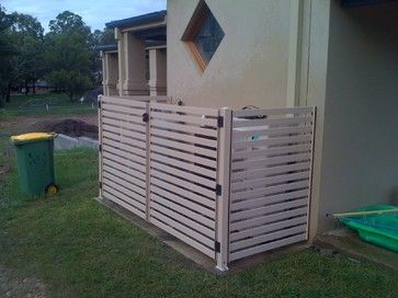 a fence that is next to a building with a green trash can in front of it