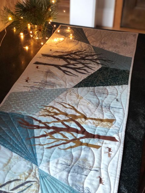 a quilted table runner with trees on it