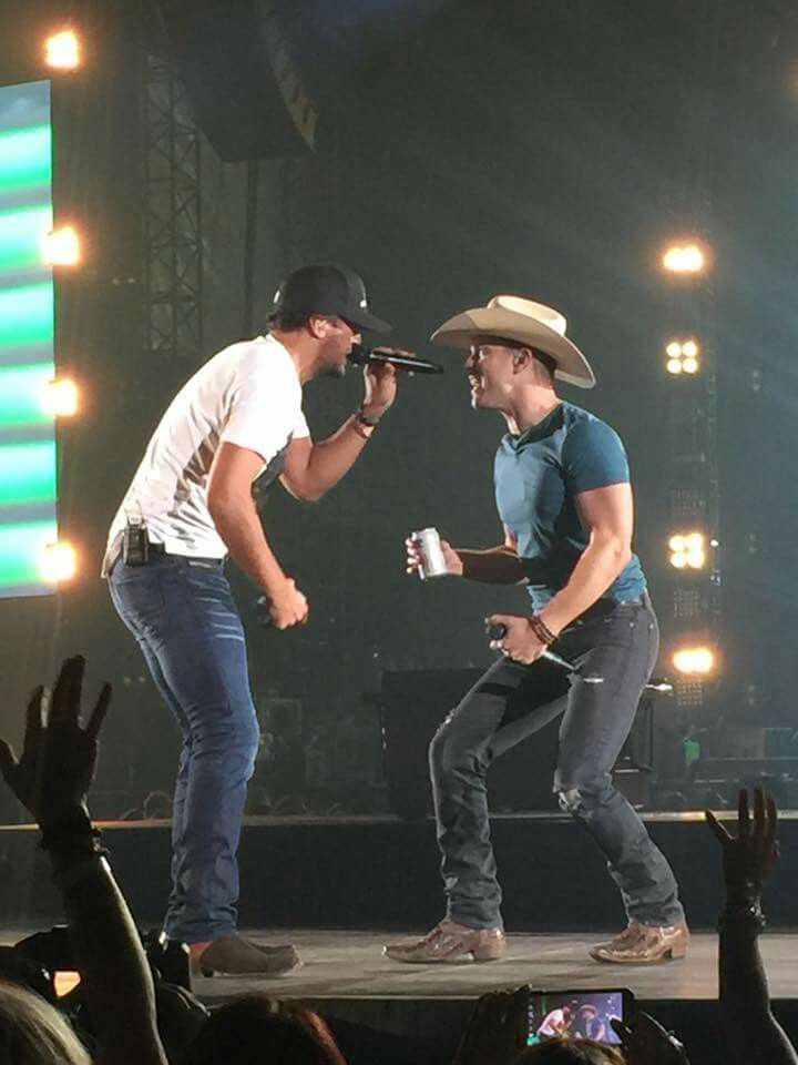 two men standing on top of a stage with microphones in their hands and people watching