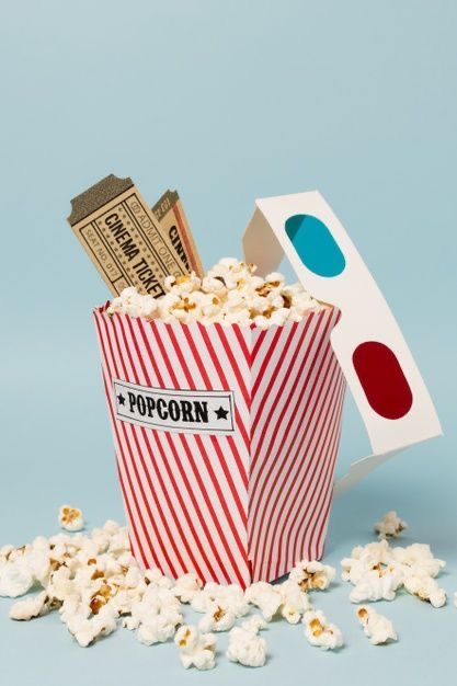 popcorn in a striped red and white paper cup with movie tickets scattered around it on a blue background