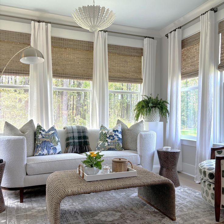 a living room filled with lots of furniture and windows covered in white curtained drapes