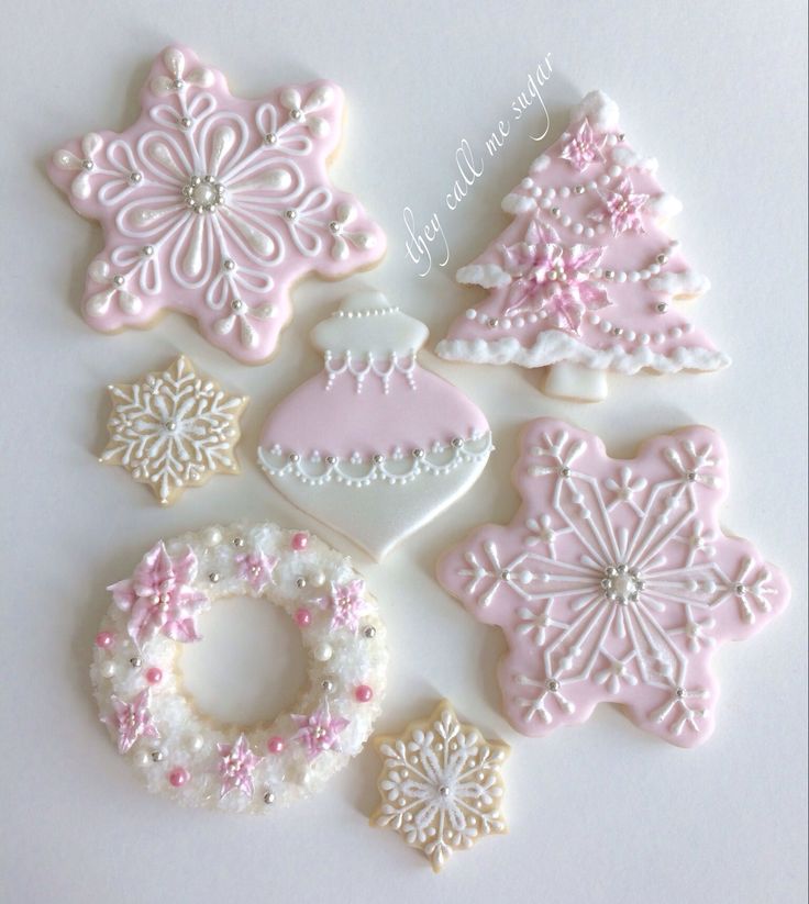 decorated cookies are arranged in the shape of christmas trees and snowflakes, on a white surface