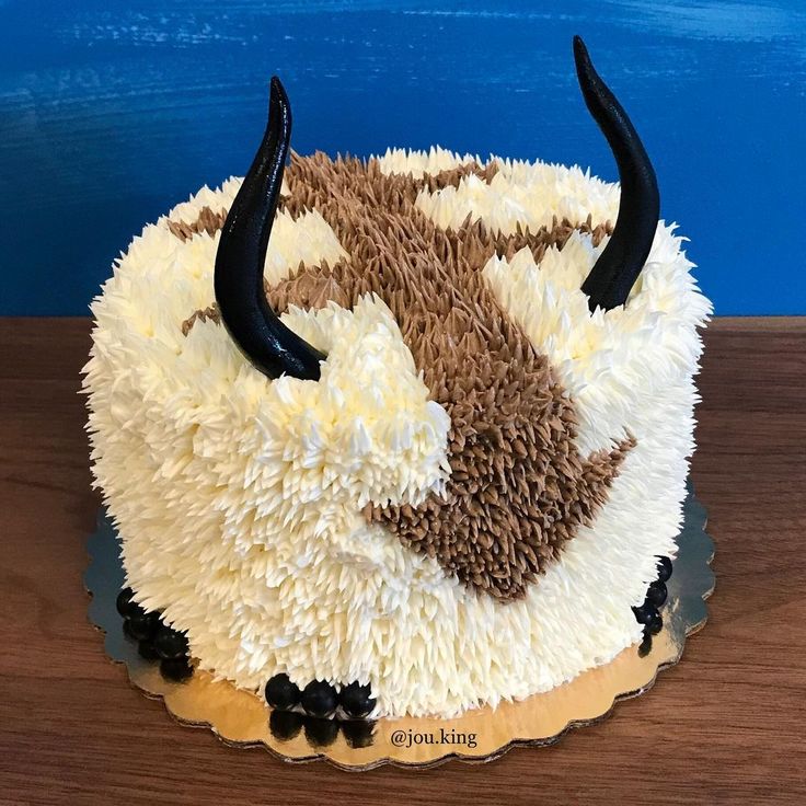 the cake is decorated with white and brown frosting, black horns on it's head