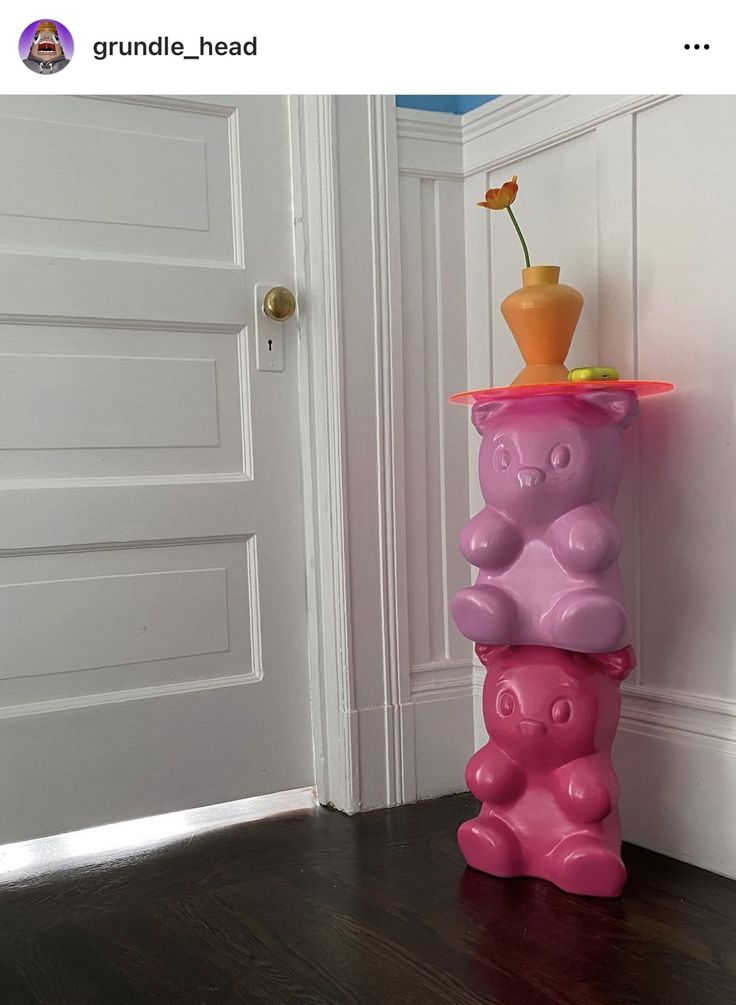 a pink and purple vase sitting on top of a wooden floor next to a door