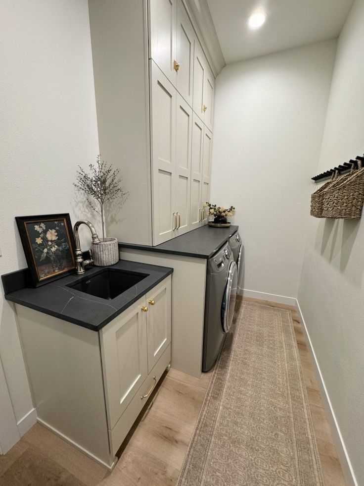 a washer and dryer in a room with white walls, wood flooring and cabinets