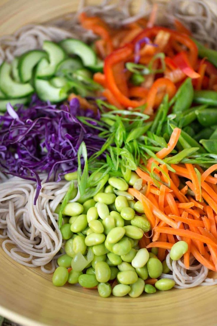 a bowl filled with vegetables and noodles on top of a table