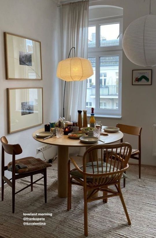 a dining room table with two chairs and a lamp hanging from the ceiling above it