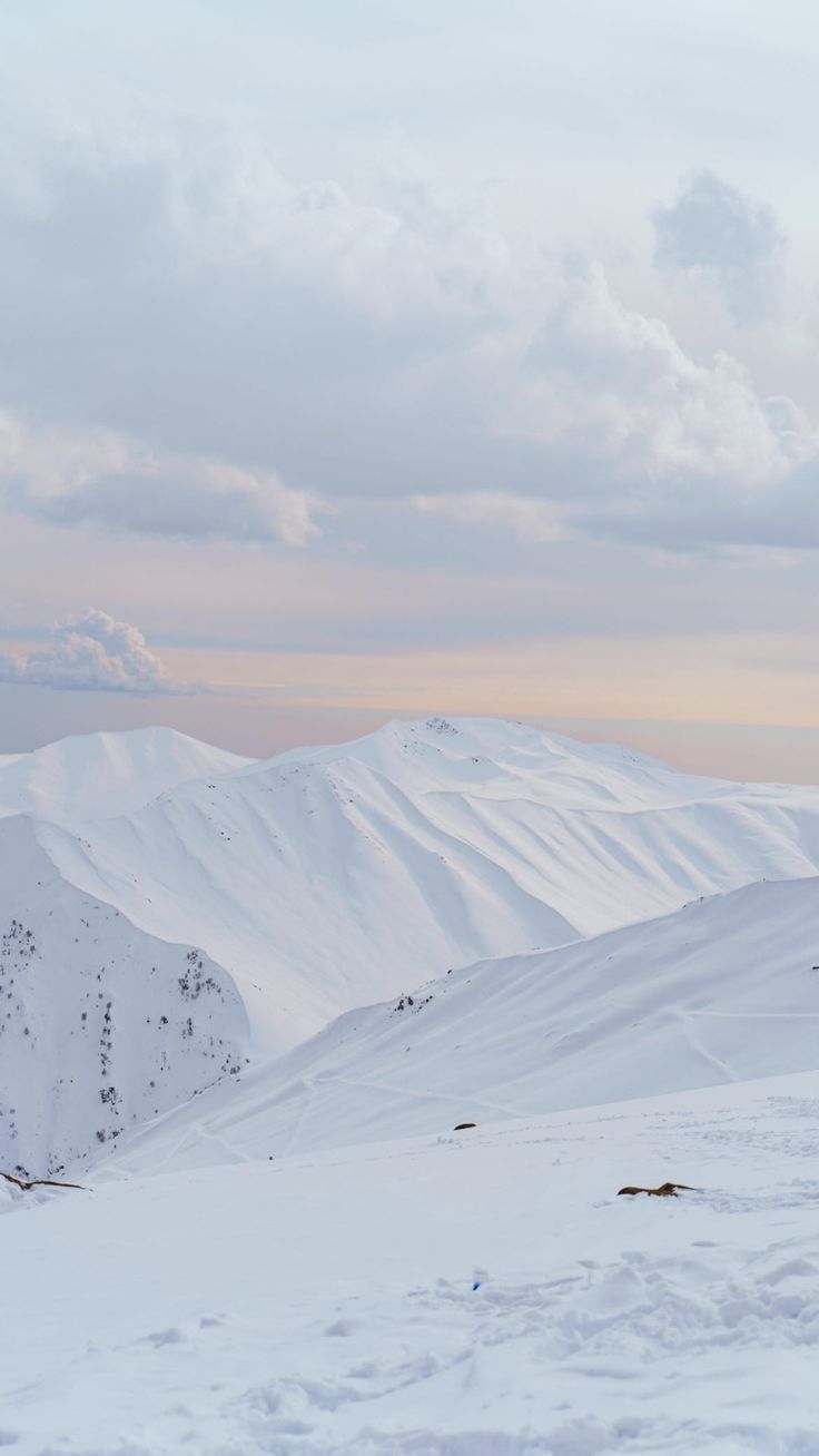 two people on skis standing in the snow with mountains in the backgroud