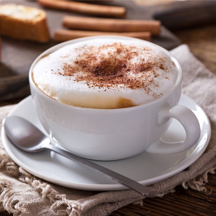 a cappuccino with cinnamon sprinkles in a white cup on a saucer