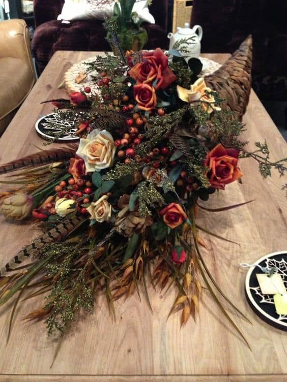 a bouquet of flowers sitting on top of a wooden table next to plates and candles