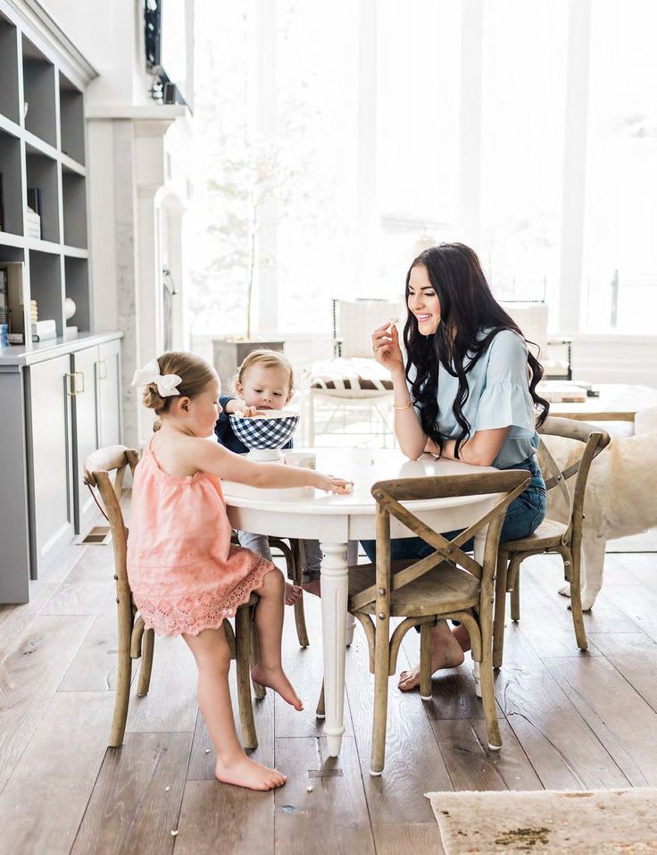 a woman sitting at a table with two children