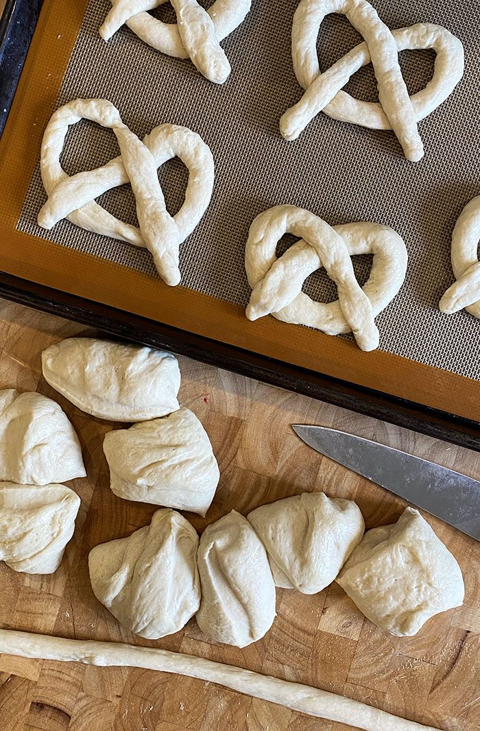 the bread is shaped into hearts and has been placed on a baking sheet with a knife next to it