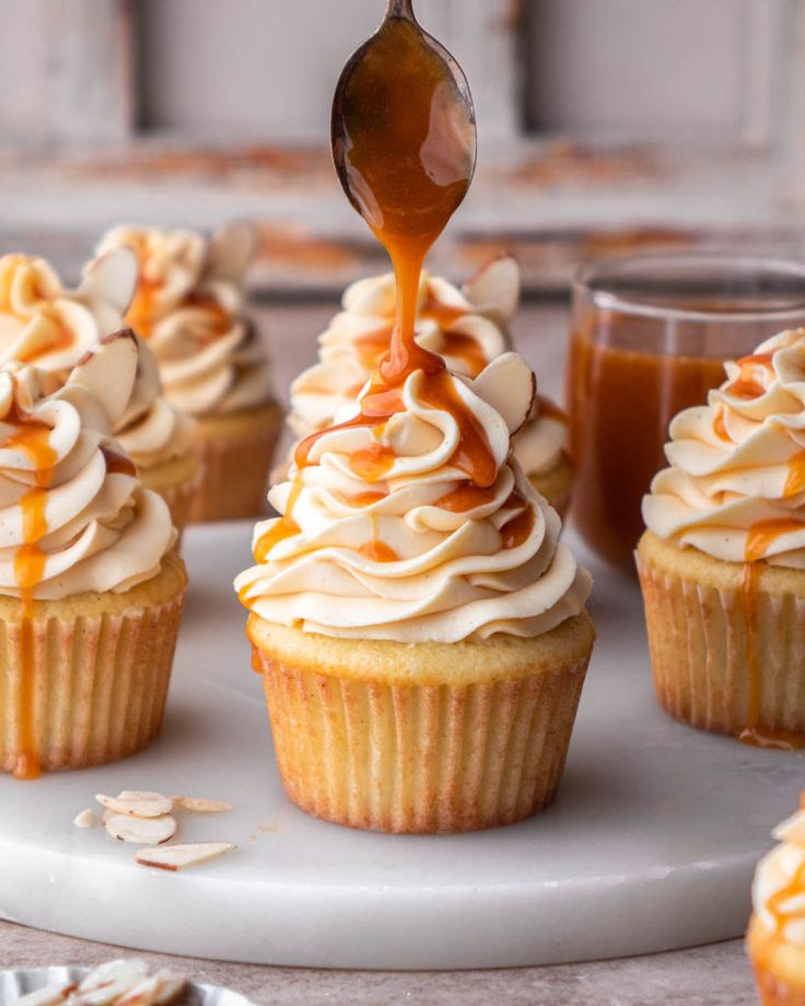 cupcakes with frosting and caramel sauce being drizzled onto them