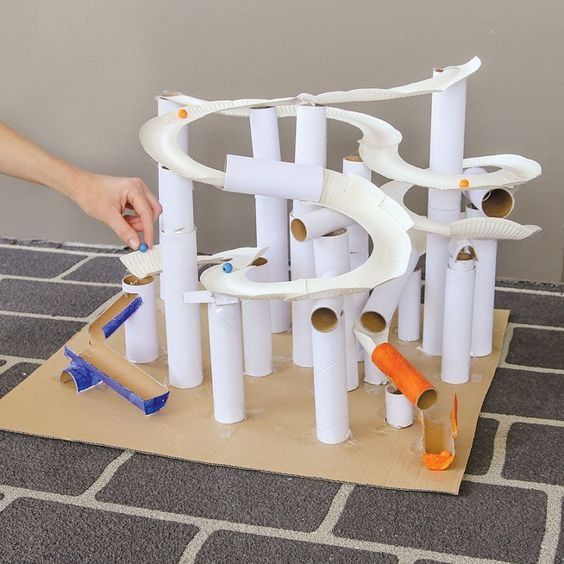 a person is building a structure out of toilet paper tubes and pipes on the floor