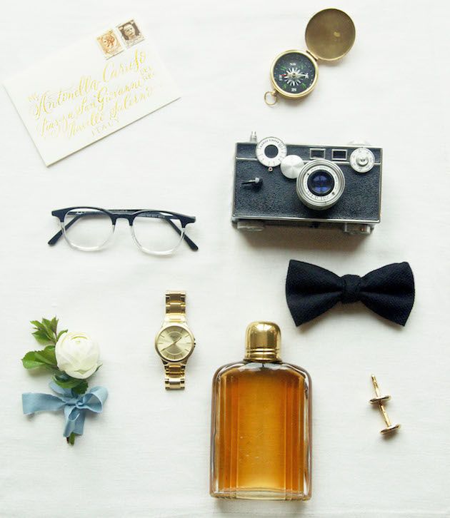 an assortment of men's accessories including a camera, watch and sunglasses are laid out on a table