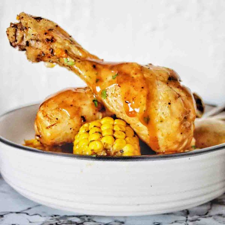 chicken with corn on the cob in a white bowl