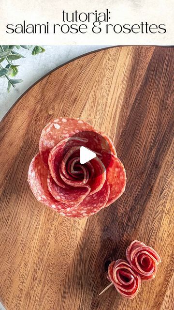 a wooden cutting board topped with slices of salami rose and prosciutto