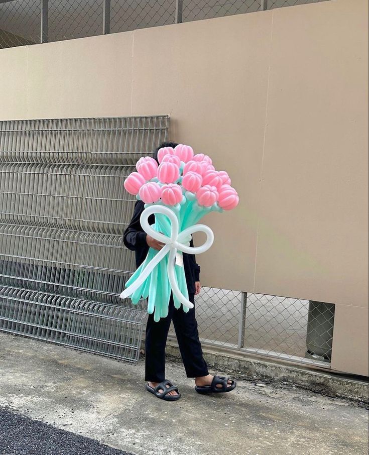 a woman is walking down the street with flowers in her hand and holding a balloon