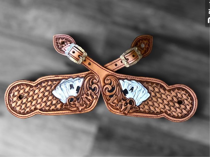 a pair of brown leather boots with white and blue designs on them, sitting on a wooden floor