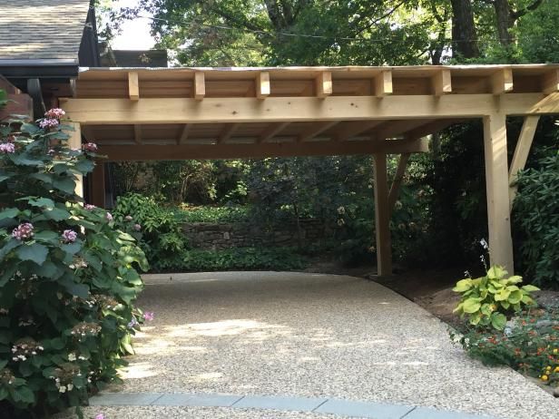 a wooden pergoline in the middle of a garden with flowers and trees around it