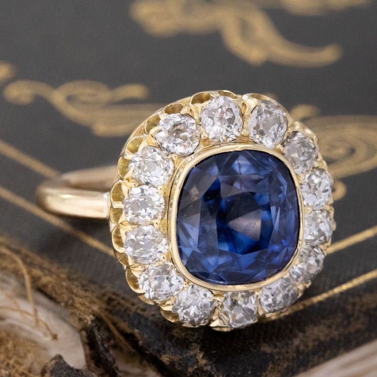 This Victorian component lived its' first life as the centerpiece to a fabulous antique bangle which didn't see much daylight, as one doesn't tend to wear big diamond cluster bangles everyday! We felt she was too beautiful to be couped up as such, so we added a simple gold shank to that center and this beautiful sapphire and old mine cut diamond cluster ring was born!The center has been designated by the UK's Gemological Certification Services as a Ceylon, no-heat sapphire with an estimated weig Vintage Sapphire Jewelry For Anniversary, Antique Brilliant Cut Jewelry For Marriage, Exquisite Cluster Rings With Single Cut Diamonds, Heirloom Diamond Jewelry With Halo Setting, Sapphire Diamond Ring With 17 Jewels For Wedding, Exquisite Cluster Diamond Jewelry, Vintage Sapphire Diamond Ring With Single Cut Diamonds, Heirloom Cluster Ring With 17 Jewels For Wedding, Cluster Jewelry With Single Cut Diamonds For Anniversary